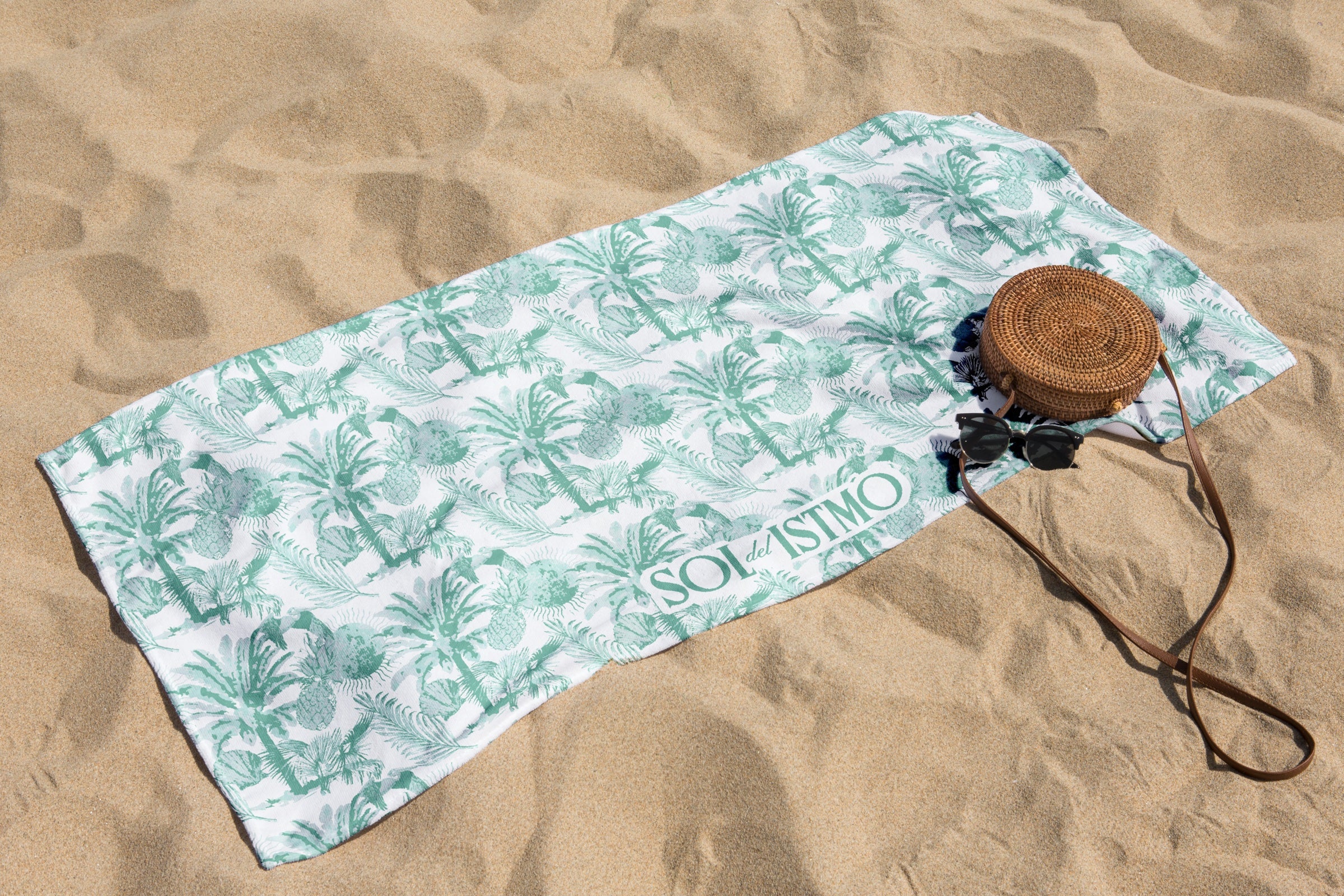 Sol del Istmo palm-print beach towel, straw bag and sunglasses on Panamanian sand